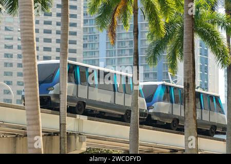 Hochzug für öffentliche Verkehrsmittel im Miami Downtown District in Florida, USA. Metrorail-Zugwagen auf hoher Eisenbahn über Straßenverkehr zwischen Stockfoto
