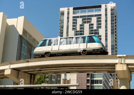 Hochzug für den öffentlichen Nahverkehr im Stadtzentrum von Miami in Florida, USA. Metrorail-Zugwagen auf der Eisenbahn über Straßenverkehr zwischen Stockfoto