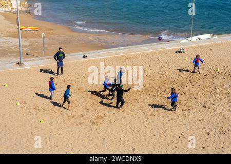 LAGOS, PORTUGAL - FERBUARY 28, 2023: Schüler spielen am 28. Februar 2023 Fußball an einem Strand in Lagos, Portugal Stockfoto