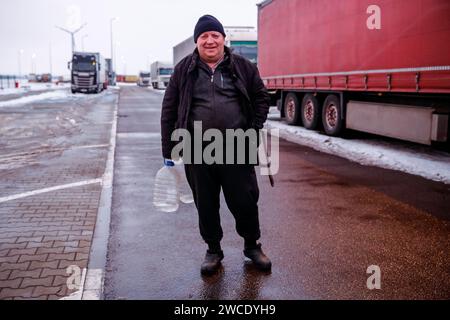 Medyka, Polen, 15. Januar 2024. Ein LKW-Fahrer steht vor Lkws, während er auf einem Parkplatz auf der Autobahn A4 wartet, um die Polnisch-ukrainische Grenze zu überqueren, während der Streik der polnischen verkehrsgewerkschaft andauert. Die union verlangt eine Neuverhandlung der Verkehrsabkommen zwischen der Ukraine und der Europäischen Union. Die Demonstranten blockierten drei Übergänge für den Lkw-Transport, sodass nur vier Lkw pro Stunde zugelassen wurden, ohne humanitäre und militärische Hilfe sowie empfindliche Chemikalien- und Nahrungsmittelgüter. Der Streik begann am 6. November. Ukrainische Fahrer sagen, dass sie mehr als 10 Tage warten, polnische Beamte sagen, dass die Warteschlange 115 Stunden beträgt. Quelle: Dominika Zarzy Stockfoto