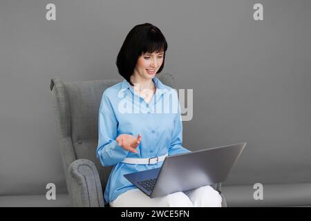 Positive Erwachsene Geschäftsfrau Mentor Lehrer Psychologin sitzt auf Sessel Konsulate sprechen in Online-Seminar auf Laptop, arbeiten mit Patienten zu Hause in r Stockfoto