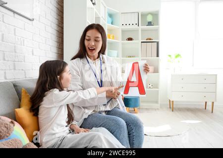 Weibliche asiatische Logopädin mit einem kleinen Mädchen, das den Buchstaben A ausspricht Stockfoto