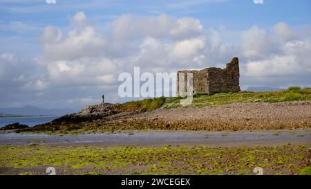 McCarthy Mor Tower House, Ballinskelligs Schloss mit einsame Figur in unmittelbarer Nähe. Baile eine Sceilg, County Kerry, Irland Stockfoto