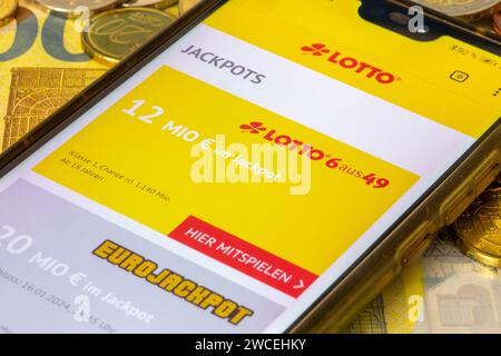 Lottosymbol: Smartphone mit Lotterie-Website, die auf Euro-Banknoten und Euro-Münzen geöffnet ist Stockfoto