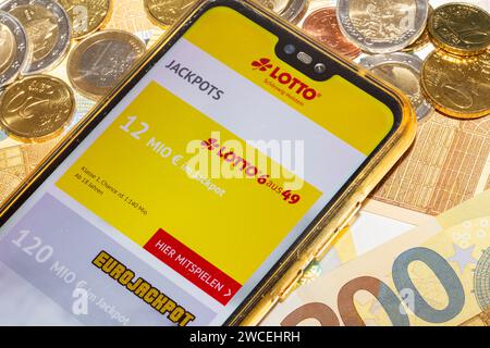 Lottosymbol: Smartphone mit Lotterie-Website, die auf Euro-Banknoten und Euro-Münzen geöffnet ist Stockfoto