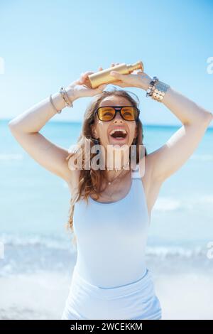 Lächelnde elegante 40-jährige Frau an der Meeresküste mit spf. Stockfoto