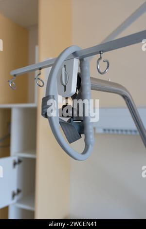 Über dem Krankenhausbett hängt adaptiver dreieckiger Metallrahmen. Galgen am Krankenhausbett eines Krankenhauses. Stockfoto