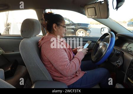 Eine hispanische Frau, die in einem geparkten Auto sitzt - November 2023 Stockfoto