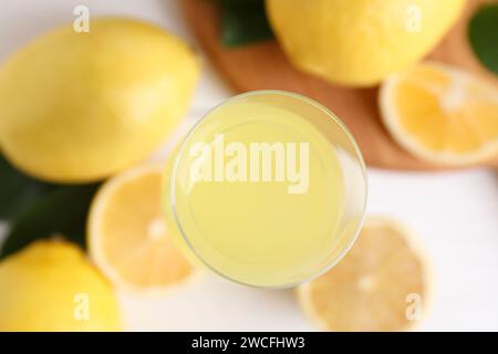 Likörglas mit leckerem Limoncello, Zitronen und grünen Blättern auf dem Tisch, Blick von oben Stockfoto