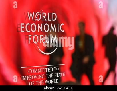 Davos, Schweiz. Januar 2024. Die Menschen gehen am Logo des World Economic Forum (WEF) in Davos, Schweiz, am 15. Januar 2024 vorbei. Die WEF-Jahrestagung 2024 wurde hier am Montag eröffnet. Angesichts der zunehmenden globalen Spaltung und Unsicherheit hat die 54. Jahrestagung des WEF führende Vertreter aus aller Welt zu einer Woche lang zusammengebracht, um die Zusammenarbeit zu verbessern und Partnerschaften zu pflegen. Quelle: Lian Yi/Xinhua/Alamy Live News Stockfoto