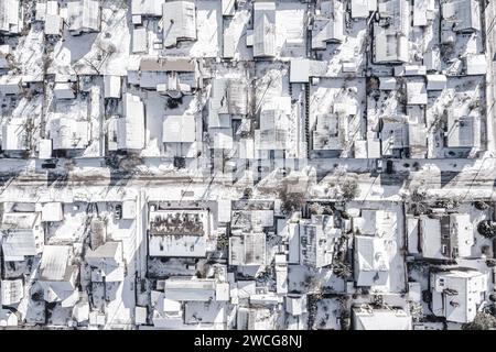 Schneebedeckte Dächer im Wohngebiet der Vororte. Luftaufnahme von oben aus der fliegenden Drohne. Stockfoto