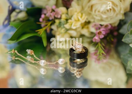 Goldener Ehering auf floralem Hintergrund, Hochzeitshintergrund Stockfoto