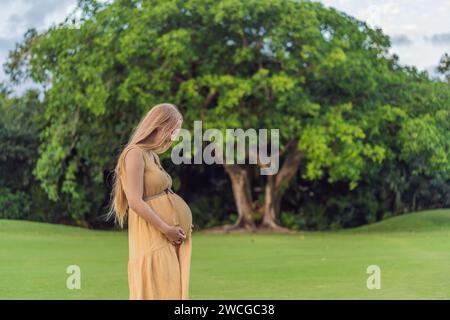 Ruhige Szene, in der eine schwangere Frau friedliche Momente im Park genießt, die Ruhe der Natur genießt und während ihrer Schwangerschaft Trost findet Stockfoto