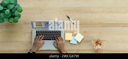 Hochwinkelansicht eines Mannes, der mit einem Laptop am Schreibtisch sitzt und sich auf seine Arbeit konzentriert. Stockfoto