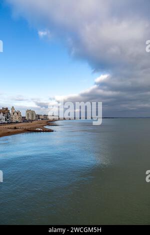 Ein Blick entlang des Strandes vom Eastbourne Pier, mit dramatischen Wolken über Ihnen Stockfoto