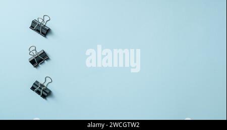 Draufsicht von drei schwarzen Büroklammern auf blauem Hintergrund Stockfoto