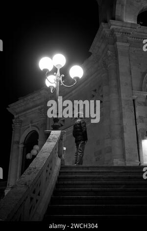 Ein Gentleman, der am Abend die Bastione di San Remy in Cagliari ansieht: Eine besinnliche Szene, die den nächtlichen Charme der Stadt einfängt Stockfoto
