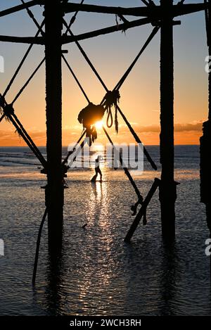 Brighton UK 16. Januar 2024 - Ein Schwimmer fährt an einem eiskalten Morgen am Brighton Palace Pier ins Meer, wenn die Sonne aufgeht und Schnee für einige Teile Großbritanniens prognostiziert wird: Credit Simon Dack / Alamy Live News Stockfoto