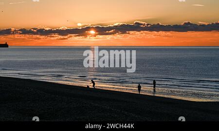 Brighton UK 16. Januar 2024 - Wanderer bei Sonnenaufgang am Brighton Beach an einem eiskalten Morgen mit Schneevorhersage für einige Teile Großbritanniens heute : Credit Simon Dack / Alamy Live News Stockfoto