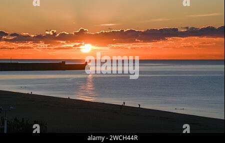 Brighton UK 16. Januar 2024 - Wanderer und Schwimmer in Brighton an einem eiskalten Morgen, wenn die Sonne aufgeht, mit Schneevorhersage für einige Teile Großbritanniens : Credit Simon Dack / Alamy Live News Stockfoto