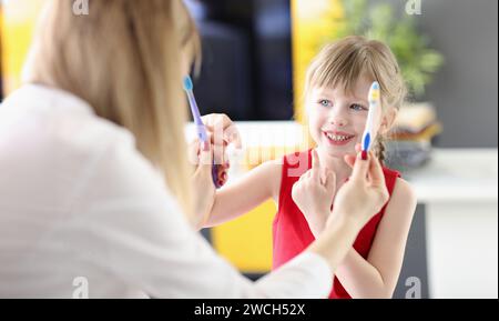 Kleines Mädchen Wahl Zahnbürste von Ärzten Hände in der Klinik Stockfoto