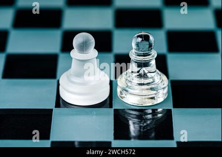 Zwei gegnerische Schachfiguren aus Glas auf einem Schachbrett aus Glas, schwarzer Hintergrund, Kopierraum Stockfoto