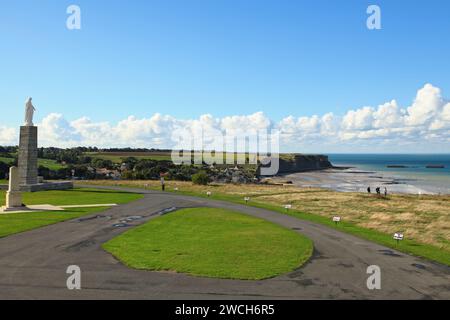 Arromanches-les-Bains, Frankreich - 14. Oktober 2012: Touristen gehen in der Nähe der Marienstatue auf der Klippe mit Blick auf die Überreste der Mulbe Stockfoto