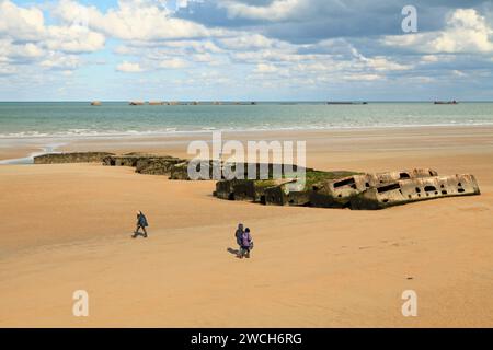 Arromanches-les-Bains, Frankreich - 14. Oktober 2012: Menschen gehen an den Überresten des Maulbeerhafens vorbei. Die Mulberry harbours waren temporär tragbare harb Stockfoto