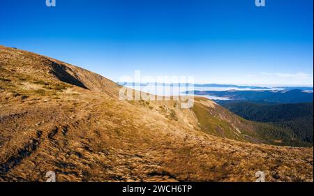 Grasbewachsener Hang einer Bergkette vor blauem, klarem Himmel. Stockfoto