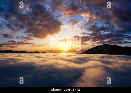 Wunderschöner Sonnenaufgang in den Bergen. Malerische Landschaft mit dramatischem Himmel über dicken Wolken im Bergtal. Drohnenansicht aus der Luft. Stockfoto