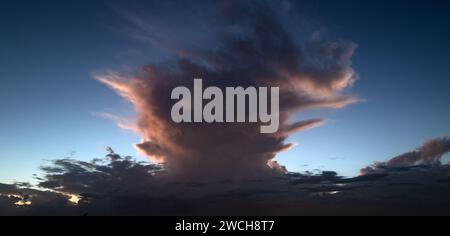 Tropischer Sturm. Wunderschöner Sonnenuntergangshimmel mit Wolken. Himmelblaues und orangefarbenes Licht der Sonne durch die Wolken am Himmel. Hintergrund dunkler Wolken davor Stockfoto