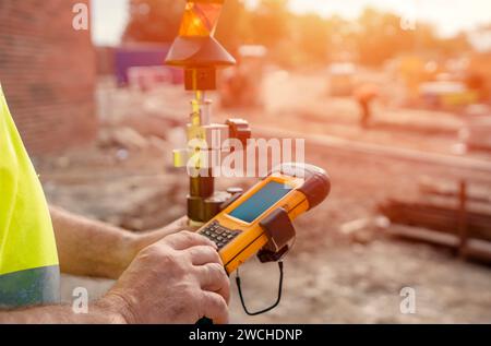 Bauingenieur-Vermessungsleiter mit robustem Tablet-Controller-Computer zur Bedienung der EDM-Gesamtstation für das Aufstellen und Vermessen von Nahaufnahmen Stockfoto