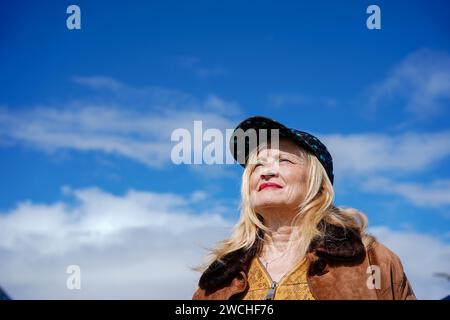 Porträt einer Reifen Frau mit modischem Hut, die mit blauem Himmel im Hintergrund aufblickt Stockfoto