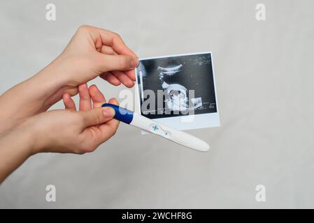 Ultraschallbild und positiver Schwangerschaftstest in der Hand eines Mädchen-Nahaufnahmen Stockfoto