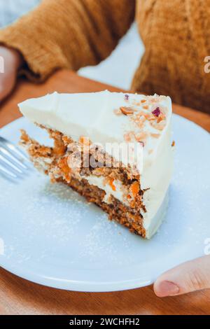 Vertikales Bild einer Scheibe Karottenkuchen, serviert auf weißem Teller auf dem Tisch im Café, Konditorei-Konzept, Kopierraum Stockfoto