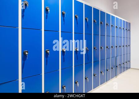 Reihe blauer Metallschränke an einer Wand mit Schlüssel in einem Schloss Stockfoto