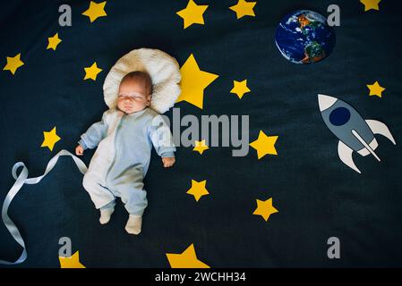 Der Junge schläft am Hintergrund des Sternenhimmels mit einer Rakete und einem Planeten. Das Konzept des Astronauten zum Weltraum Stockfoto