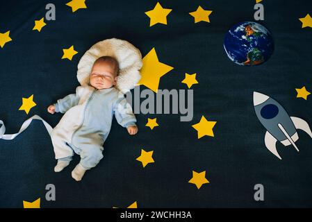 Der Junge schläft am Hintergrund des Sternenhimmels mit einer Rakete und einem Planeten. Das Konzept des Astronauten zum Weltraum Stockfoto