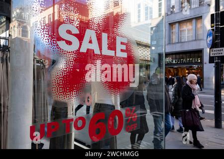 Die Leute, die auf der Oxford Street einkaufen, gehen am 15. Januar 2024 in London, Großbritannien, vorbei an großen Verkaufsschildern in Rot und weiß für die großen Einkaufsläden in der High Street. Es ist Zeit für die Winterverkäufe, und die meisten Geschäfte werben für große Preissenkungen. Schnäppchen gibt es und die Einkaufsstraßen sind voll. Die Oxford Street ist ein bedeutendes Einkaufszentrum im West End der Hauptstadt und ist Europas geschäftigste Einkaufsstraße mit rund einer halben Million Besuchern der rund 300 Geschäfte, von denen die meisten Mode- und High Street-Bekleidungsgeschäfte sind. Stockfoto