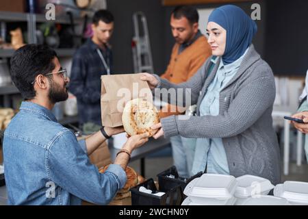 Seitenansicht Porträt einer Frau aus dem Nahen Osten, die Kopftuch trägt und im Flüchtlingshilfezentrum kostenlos Nahrung erhält Stockfoto