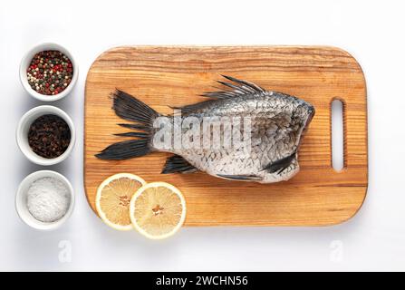 Geschälter Karpfenfisch auf einem Schneidebrett mit Zitronenscheiben und Gewürzen, fertig zum Kochen. Gesunde Ernährung. Stockfoto