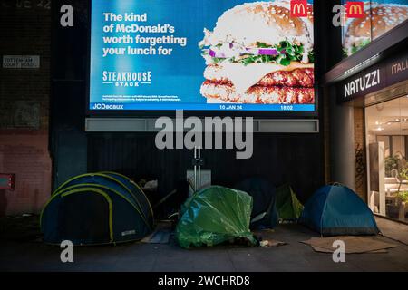 Zelte für Obdachlose und Raubschläfer an der Tottenham Court Road, unter einer digitalen Werbetafel, im Zentrum von London, England, Großbritannien Stockfoto