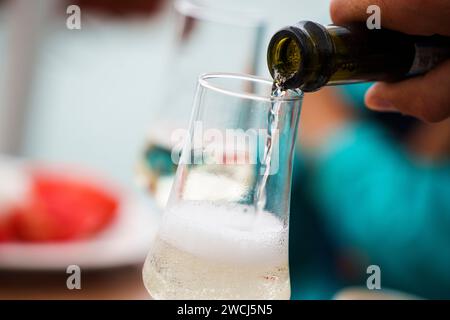 Nahaufnahme eines Champagners, der aus einer Flasche in ein Sektglas gegossen wird. Stockfoto