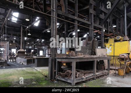 Innenraum des Schmiedewerkes, in dem Männer arbeiteten, um erhitztes Metall von Hand und Maschine zu Formen, im Queen Victoria Museum in Inveresk Stockfoto