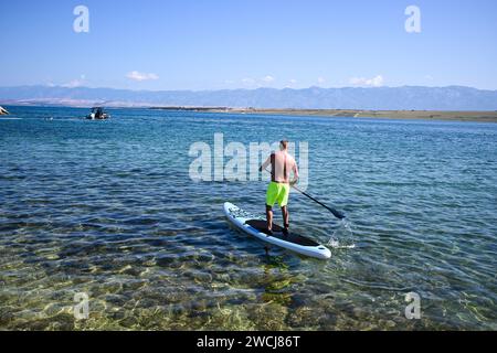 Ein Typ rudert auf einem Paddleboard. Stockfoto