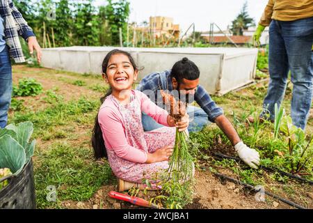 Indische Familie pflücken Bio Karotten aus Bio Gemüse Garten Outdoor - vegetarisch, gesunde Lebensmittel und Bildungskonzept - Fokus auf Kindergesicht Stockfoto