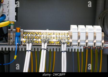 Ein Elektriker, der in einem Schaltschrank arbeitet, prüft Kabel mit einem Tester. Stockfoto