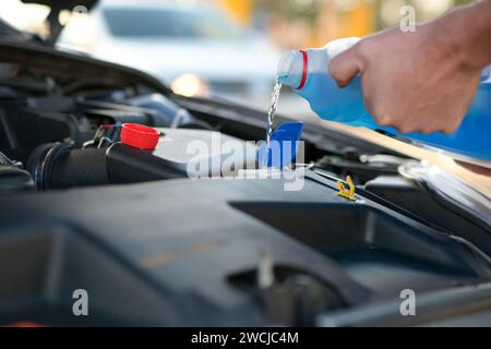 Der Mechaniker fügt den Waschanlagen Wasser hinzu, kümmert sich um das Fahrzeug, die Nahaufnahme und den unscharfen Hintergrund. Stockfoto