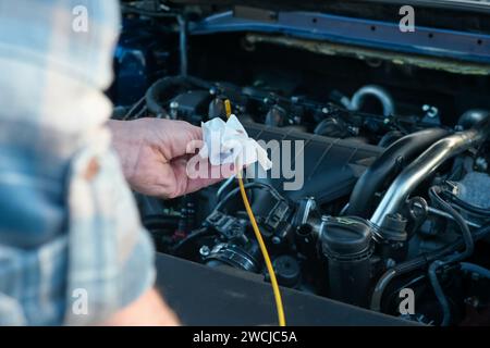 Der Mechaniker überprüft den Ölstand im Fahrzeug, aus Nahsicht und auf einem unscharfen Hintergrund. Stockfoto