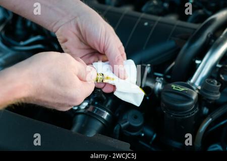 Der Mechaniker überprüft den Ölstand im Fahrzeug, aus Nahsicht und auf einem unscharfen Hintergrund. Stockfoto